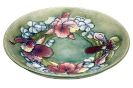 Moorcroft bowl decorated in Orchid pattern on a green ground