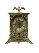 Small bedside table clock in a pierced brass case on a splayed plinth