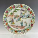A Chinese famille verte porcelain plate, circa 1800, decorated with figures in a garden, within a