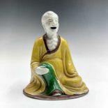 A Chinese sancai-glazed figure of a seated monk, 18th/19th century, height 14cm, width 11cm, depth