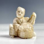 A Japanese okimono of a figure with a basket of clothes, Meiji period, with age related cracks,