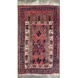 An Afghan prayer rug, circa 1930, the madder mihrab with stylised plants, within multiple borders,