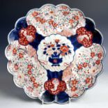 A Japanese Imari lobed porcelain dish, Meiji period, the central medallion enclosing a vase of