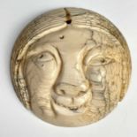 A Japanese netsuke portraying a smiling Okame mask, 19th century, diameter 5.3cm.