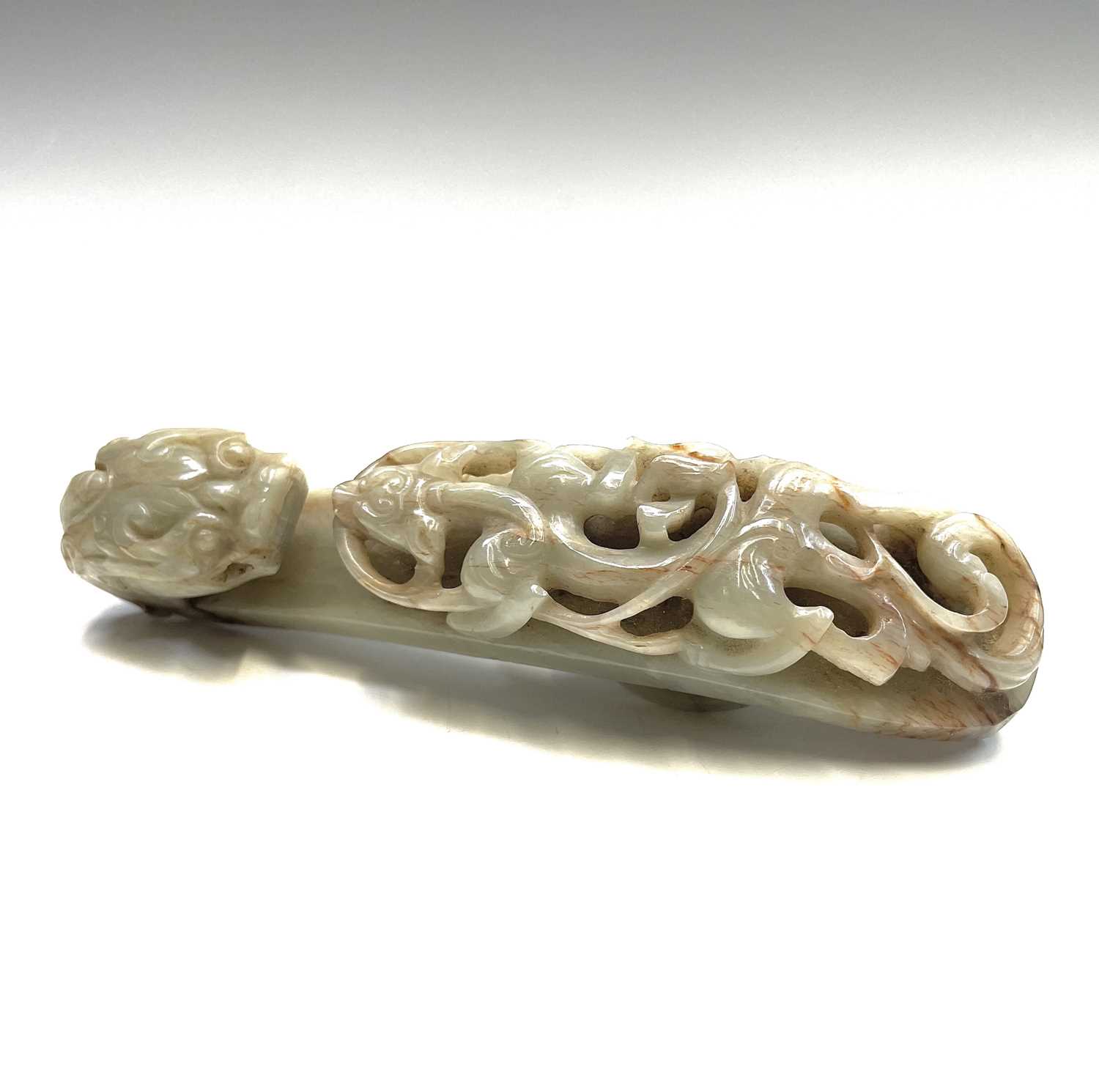 A Chinese jade belt hook, Qing Dynasty, carved with a scroll form chilong facing a dragon head