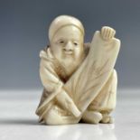 A Japanese netsuke of a seated man holding a scroll, Meiji period, circa 1890, height 3.5cm, width