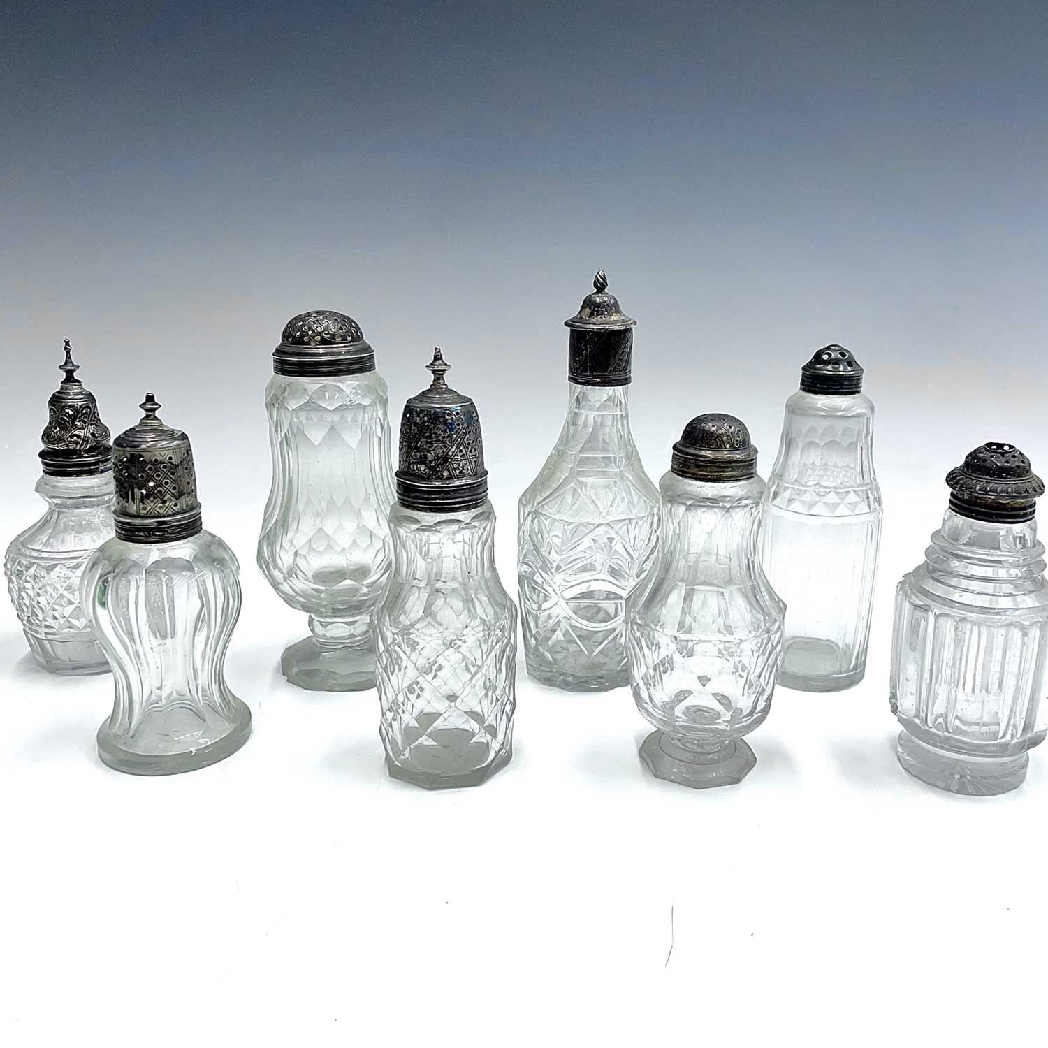 A collection of eight Georgian facet and cut glass cruet bottles with silver lids, all unmarked, the