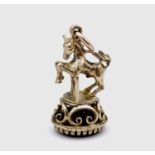 A 9ct hallmarked gold seal fob modelled as a horse jumping a stile, with oval carnelian matrix,