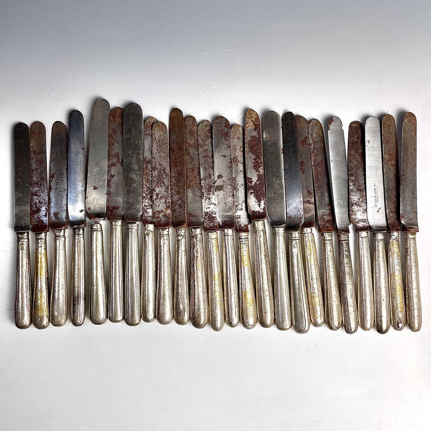 A George III harlequin set of 24 knives with steel blades and silver filled handles, lengths 20-