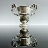 An Edwardian silver small pedestal trophy cup with twin scroll handles, maker George Nathan & Ridley