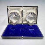 A George V cased pair of scallop shell butter dishes by Elkington & Co, together with one butter