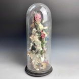 A Victorian glass dome, containing a display of artificial flowers in a vase, on ebonised stand,