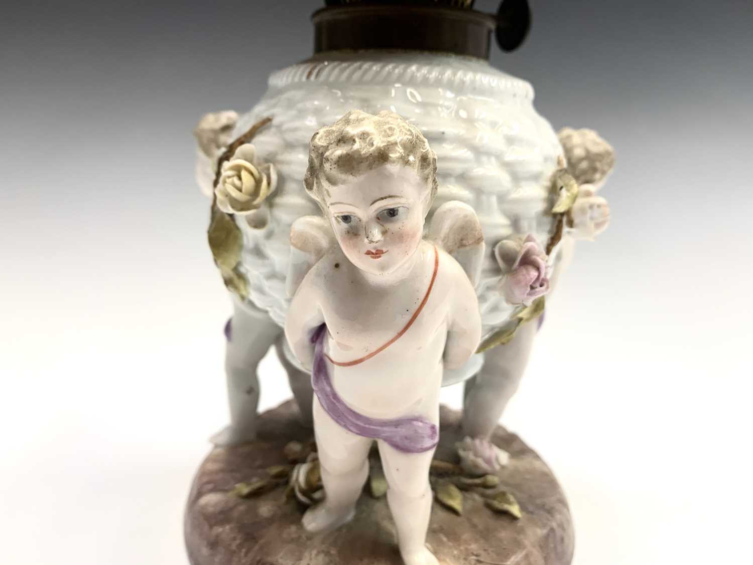 A German porcelain oil lamp base, circa 1900, modelled as a basket supported by three cherubs, - Image 3 of 10