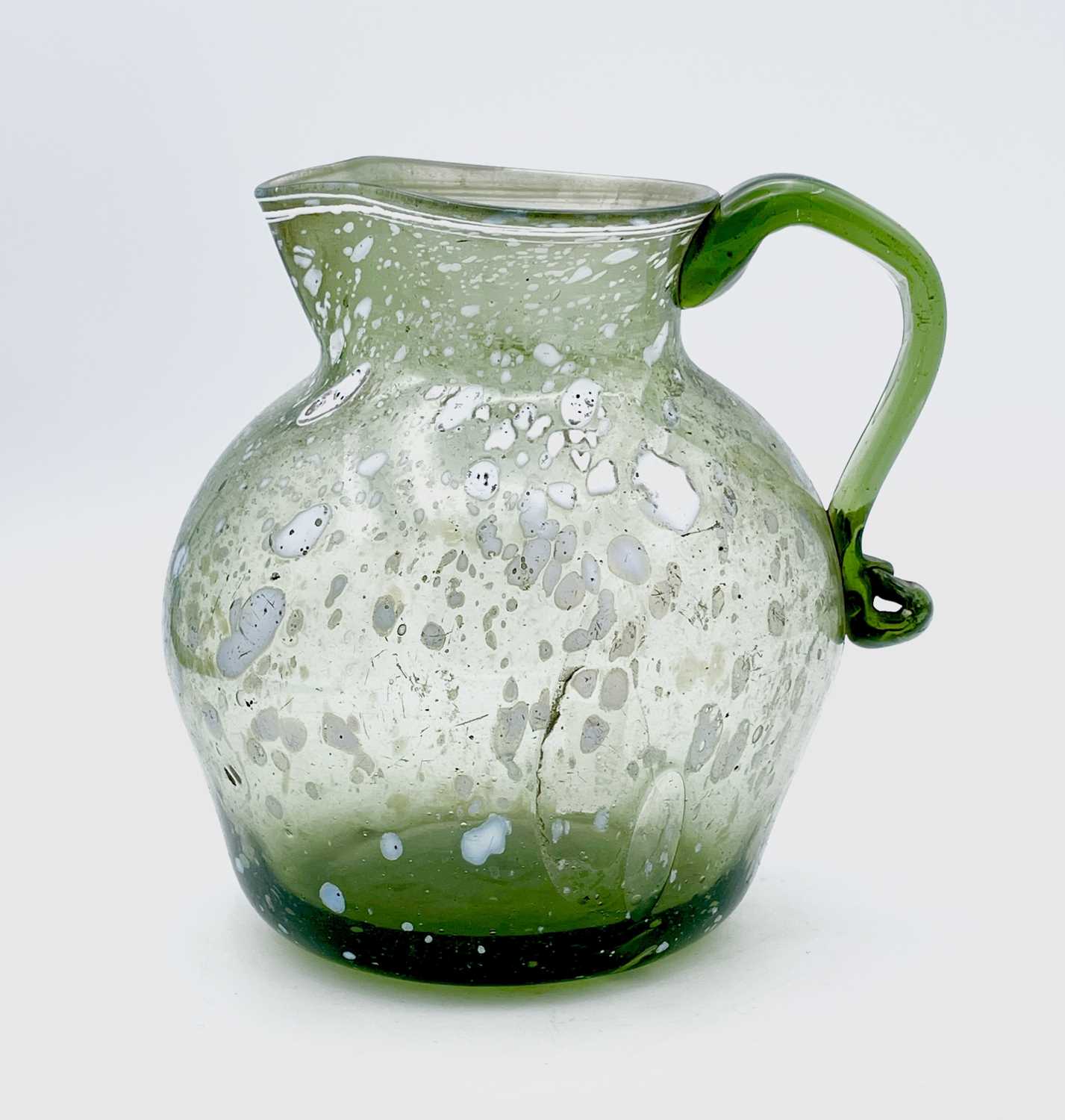 A Nailsea type glass jug, circa 1800, pale green with opaque white mottling, height 15cm.Provenance: