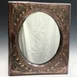 A Glasgow School Arts and Crafts copper framed mirror embossed with stylised flowers and sinuous