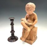 A Cornish serpentine candlestick, height 27cm, together with a terracotta figure of a boy, seated