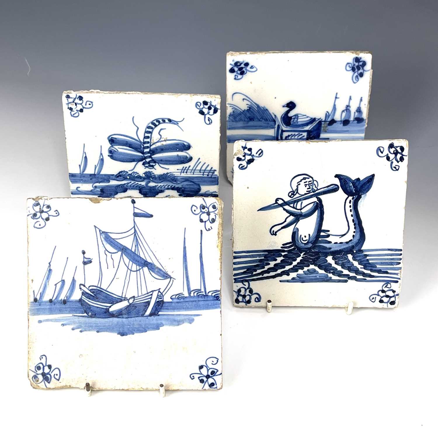 Four blue and white Dutch Delft tiles, decorated with various scenes including a flute playing
