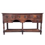 A George III oak dresser base, the rectangular moulded top above an arrangement of five drawers,