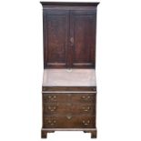 A George III oak bureau bookcase, with a part of panelled doors opening to reveal shelves, above a
