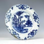 An 18th century Dutch Delft dish, decorated with a stylised tree, flowers, vase and dish, diameter