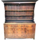 A George III oak dresser, the rack with three shelves, the lower part with an arrangement of six
