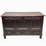 A George III oak mule chest, the hinged plain top and leaf carved frieze above a triple panelled