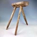 A primitive three-legged stool, 19th century, height 55cm, width of seat 30cm.There is a small
