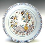 A Delft polychrome dish, 18th century, decorated with a vase of flowers, diameter 23cm.Provenance: