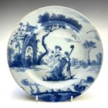 An English Delft blue and white plate, late 18th century, with a shepherd and shepherdess in a