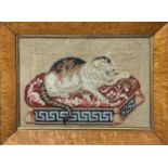A Victorian Berlin woolwork picture of a cat, seated on a cushion, with Greek key lower border,