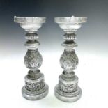 A pair of silver painted candlesticks with Indian motif designs, height 30cm.