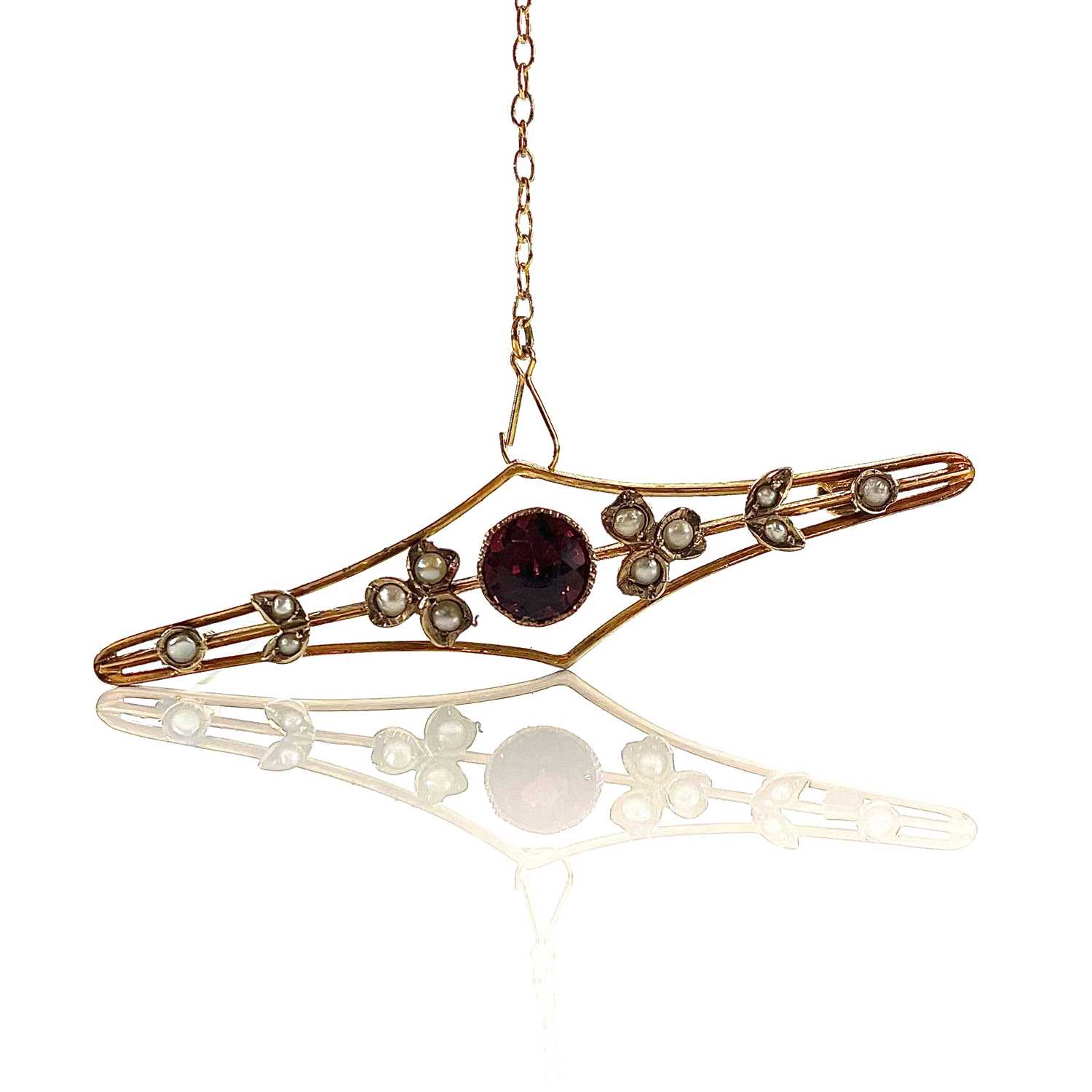 A 9ct gold garnet and seed pearl set bar brooch, base metal pin, width 57mm, weight 3.75g.