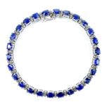 A modern 18ct white gold sapphire and diamond line bracelet, the 26 oval cut blue sapphires each