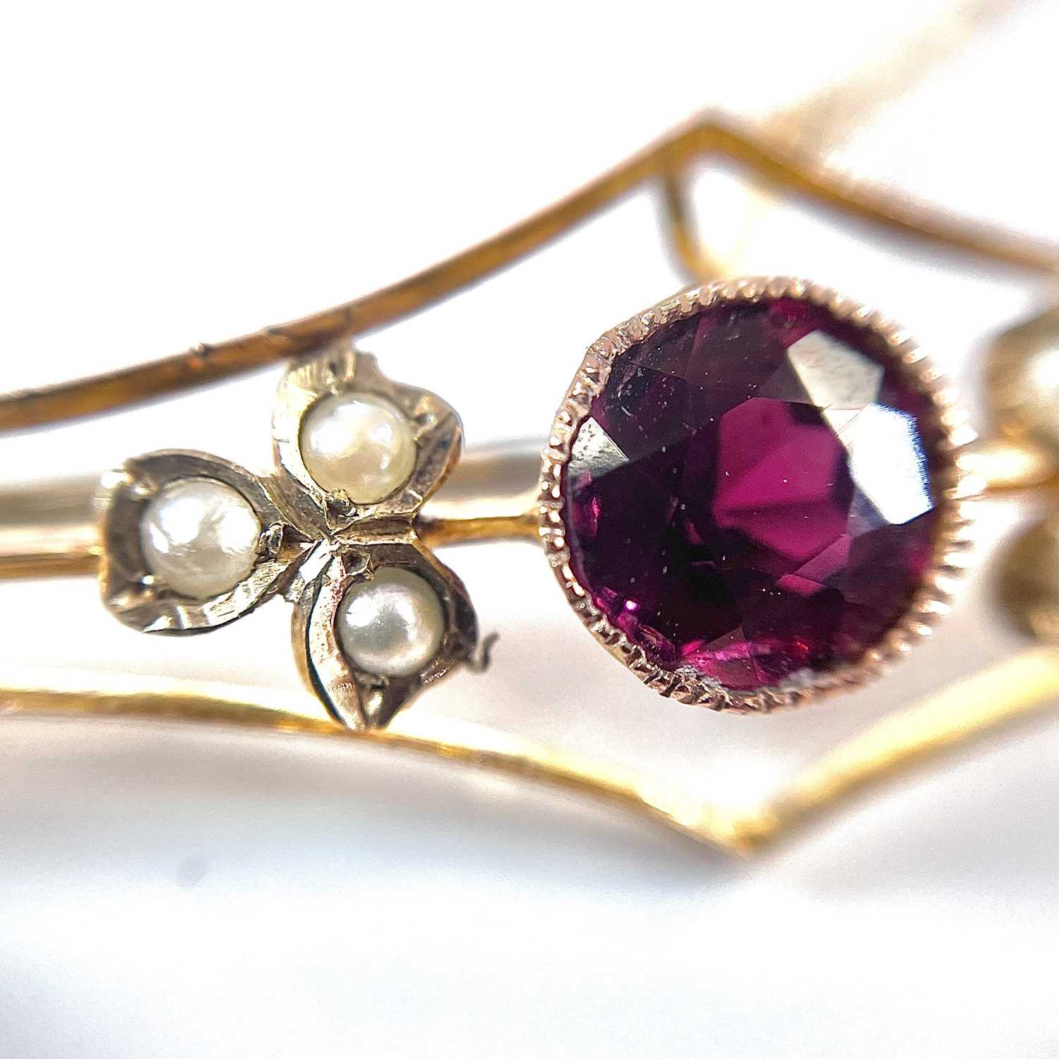 A 9ct gold garnet and seed pearl set bar brooch, base metal pin, width 57mm, weight 3.75g. - Image 5 of 7