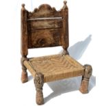 An Afghan carved wood low chair, 19th century, with a pierced back and woven seat, on turned legs,