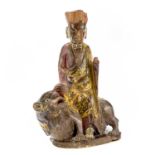 A Chinese carved and painted figure, 19th century, seated in robes wearing a high crown and riding a