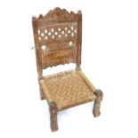 An Afghan carved wood low chair, 19th century, with a pierced back and woven seat, on turned legs,