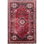 A Shiraz rug, South West Persia, the madder field with an hexagonal polychrome central medallion,