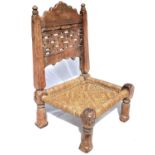 An Afghan carved wood low chair, 19th century, with a pierced back and woven seat, on turned legs,