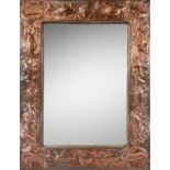 A Newlyn industrial class copper framed mirror, circa 1900, repousse decorated in typical style with
