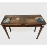 An Arts and Crafts oak double school desk, the hinged lids with painted scenes, on circular tapering