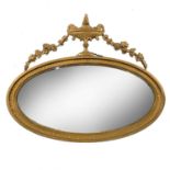 An Edwardian gilt framed oval wall mirror, of Neo-Classical form, with urn and festoon cresting,