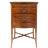 An Edwardian walnut music cabinet, slightly bow front and fitted with five drop-front drawers on