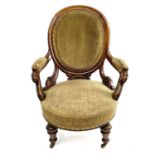 A Victorian walnut spoon back armchair, with padded back, arms, and seat and with carved and