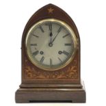 A mahogany and inlaid lancet shape mantel clock, circa 1900, with silvered dial, striking on two