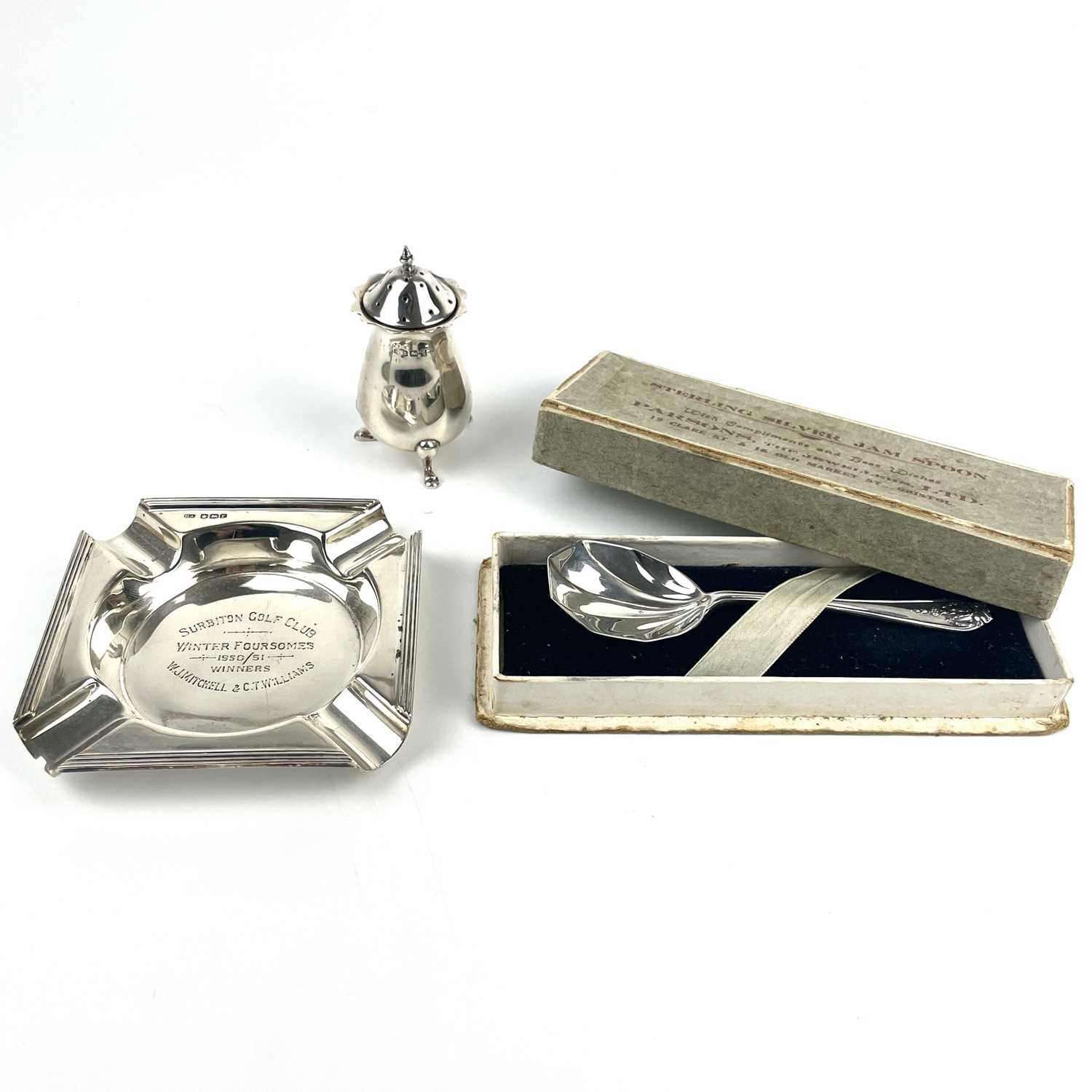 A George VI silver ashtray, a silver pepperette and a condiment spoon.