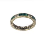 A 9ct gold white and green stone set full eternity ring.