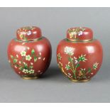 A pair of red ground and floral patterned cloisonne enamelled jars and covers 14cm x 8cm (1 with