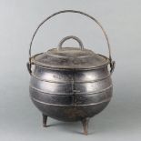 A circular iron cauldron with swing handle and lid 23cm h x 26cm diam.