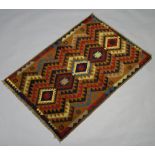 A red, brown and tan ground Belouche rug with diamond geometric design 115cm x 80cm